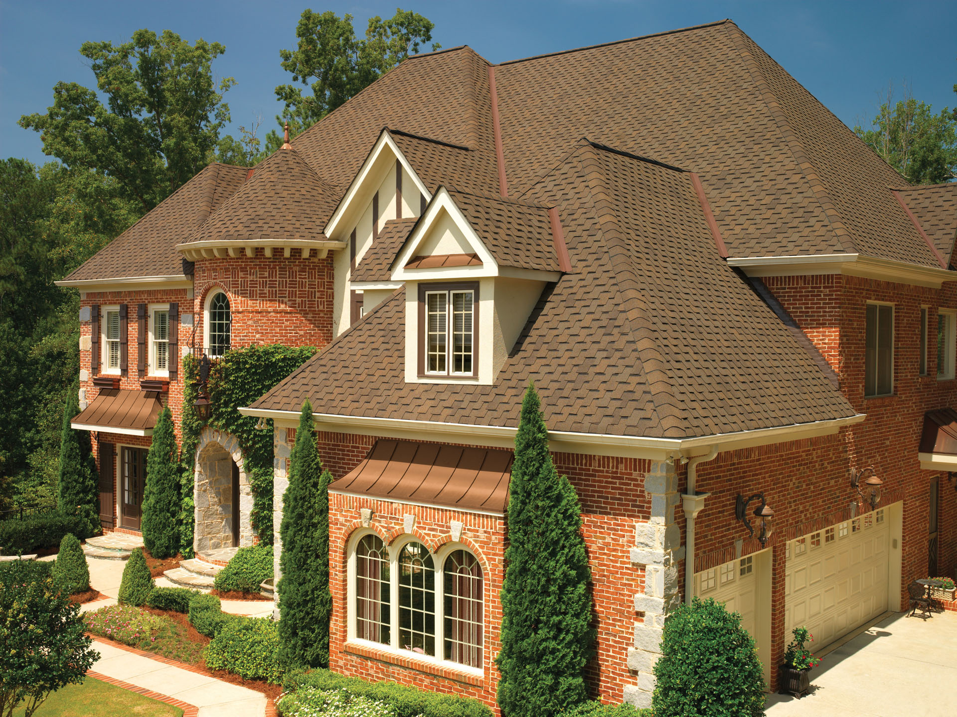 Brand-new asphalt shingles on a two story brick home, with accenting copper flashing.